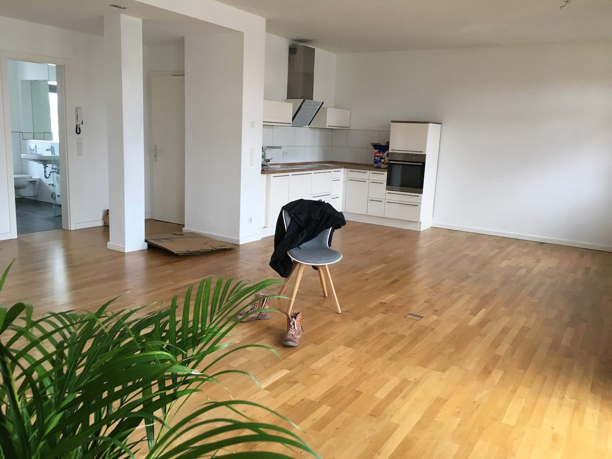 Departamento vacío y desordenado, con una silla, ropa y cajas en el piso