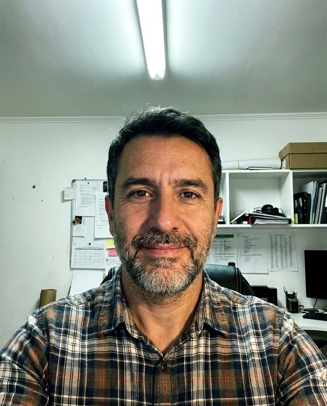 Selfie casual tomada con celular frente a una pared de oficina
